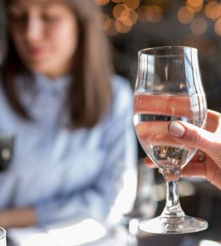 close up of a woman holding a water glass filled with acqua pannaatural mineral water