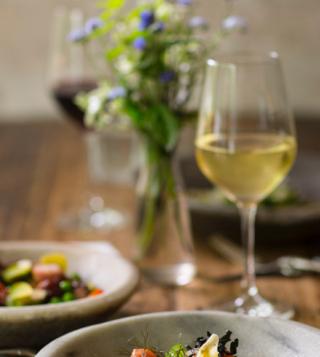 rustic table set fir dinner with food, wine, and flowers