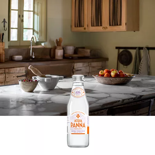 wood table with appetizers and 8 oz glass bottle acqua panna water